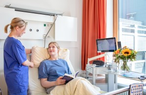 Patient:in im Bett mit Pfleger_in