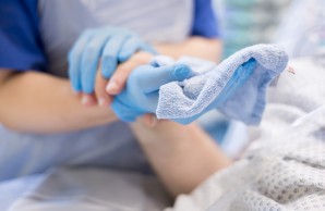 Hände eines Patienten berühren den Unterarm einer Pflegenden