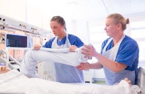 Pflegende hebt das eingewickelte Bein eines Patienten