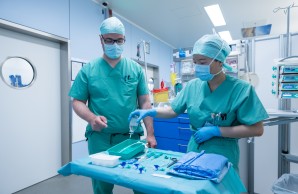 Zwei Pflegende in der Anästhesie bereiten einen Tisch mit Materialien vor.