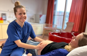 Hebammenstudentin tastet Bauch einer Schwangeren ab