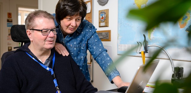 Anja und Tomas Gerlach schauen in einen Monitor, sie lächeln