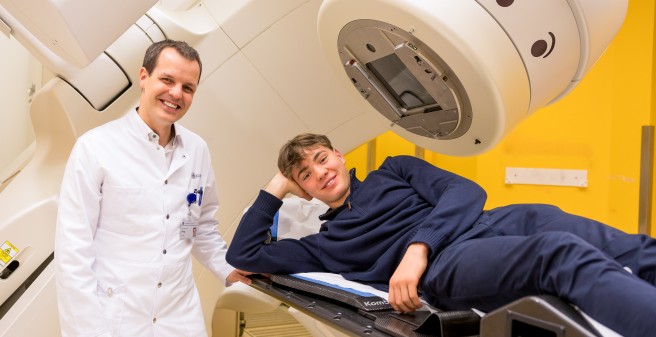 Priv.-Doz. Dr. David Krug zeigt Piet den Schwenkkopf des Linearbeschleunigers, aus dem die Strahlung auf die jeweilige Körperstelle mit dem Tumor einwirkt