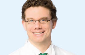 Ein Porträt-Foto. Prof Huber blickt lächelnd in die Kamera, er trägt eine Brille mit dunklem kleinen Metallgestell.