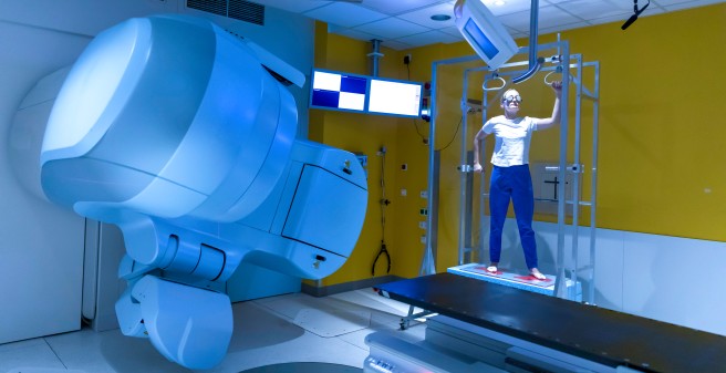 Im bestimmten Abstand zur Bestrahlungsquelle halten Patient:innen bis zu sechs verschiedene Arm- und Beinpositionen