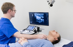 Die Schilddrüse einer jungen Frau wird gerade mit einem Ultraschallgerät untersucht