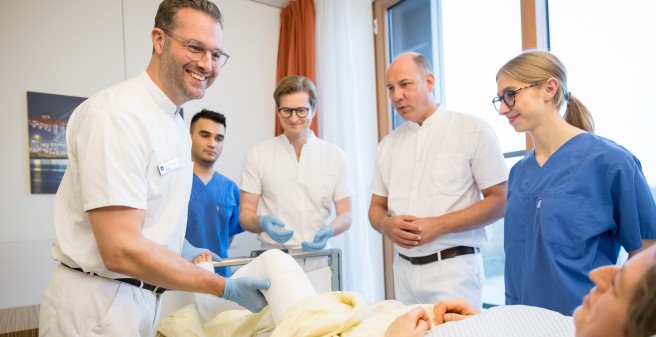  Ärzt:innen führen orthopädische Untersuchung am Patientinnenbett durch