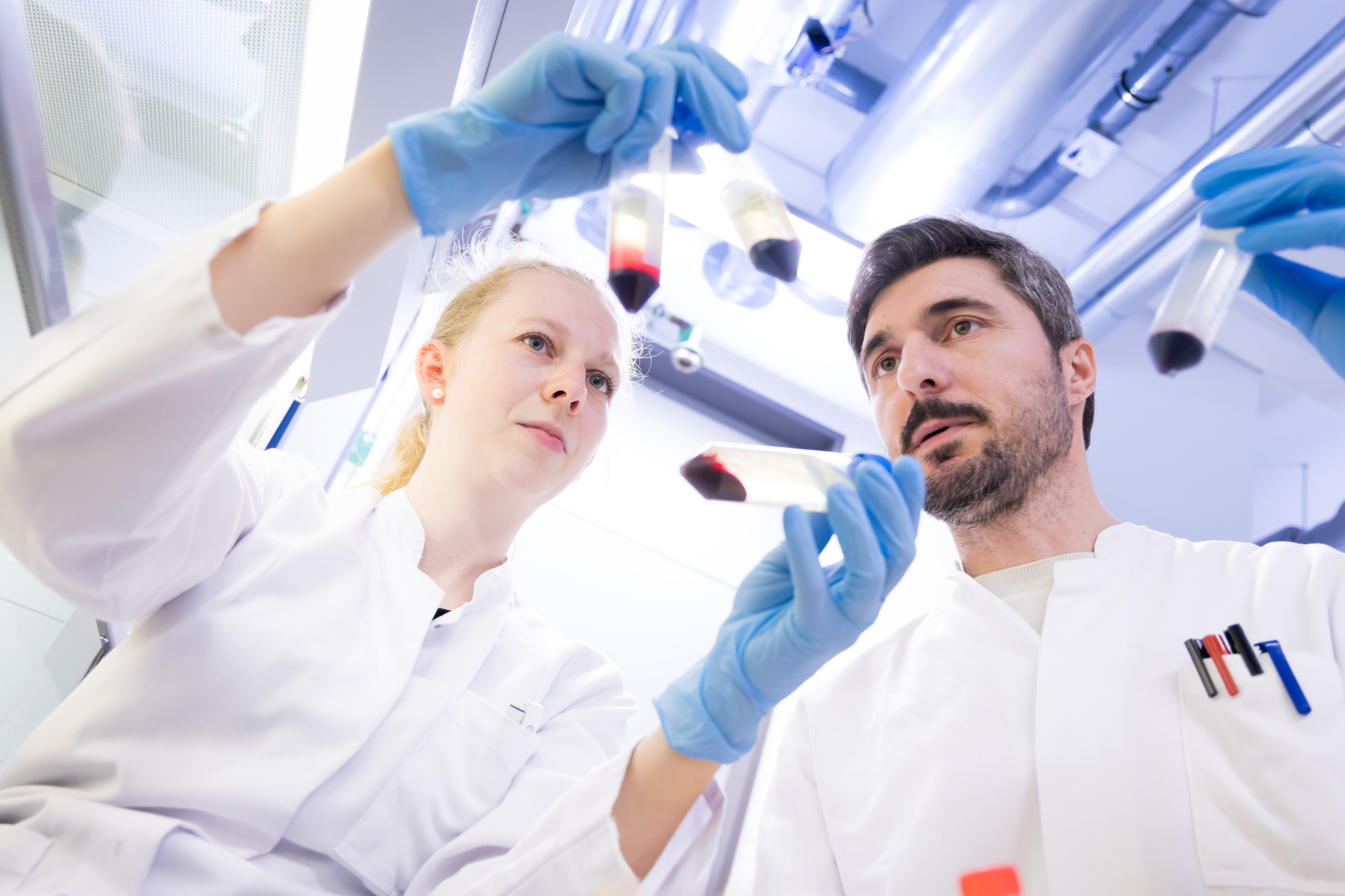 Two researchers looking together into two sample containers.