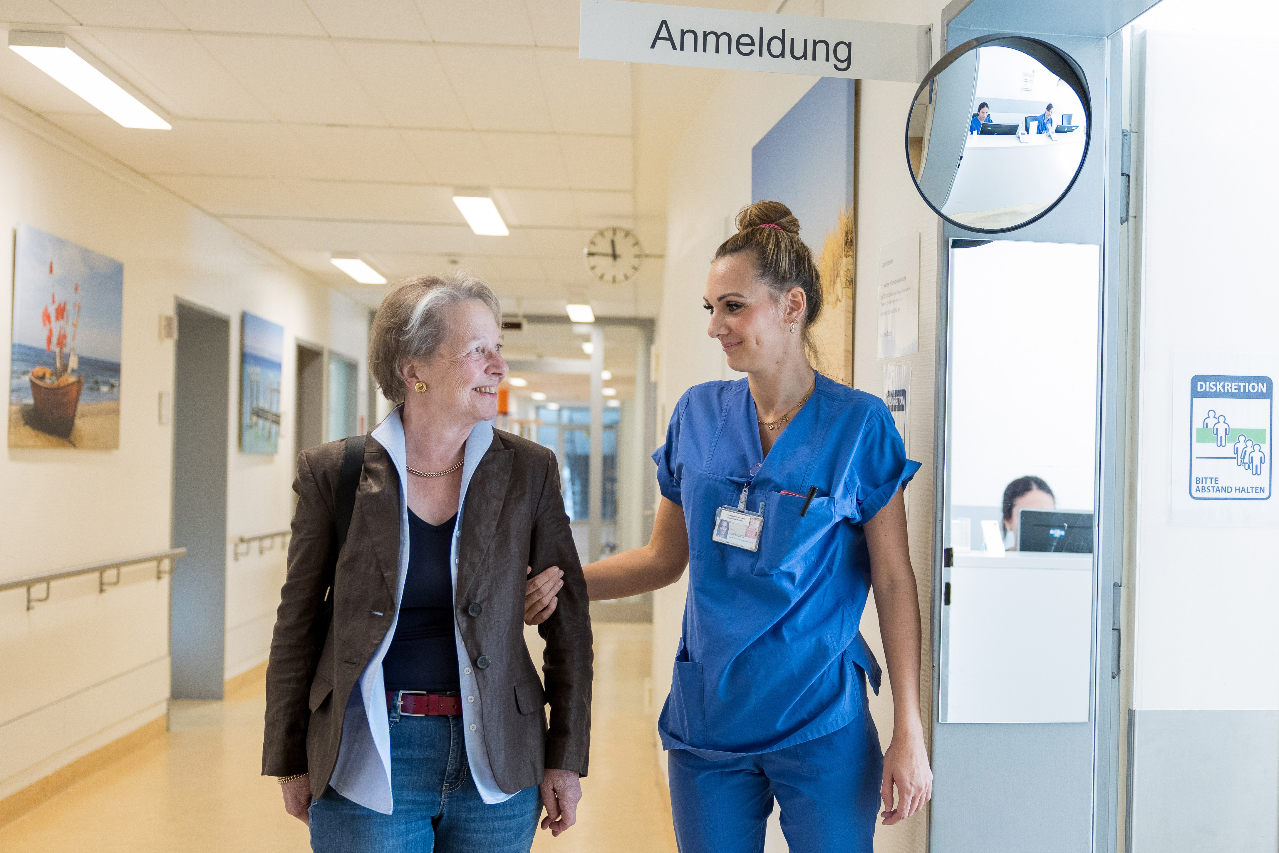 Pflegekraft und Patient:in gehen gemeinsam über den Flur der Onkologischen Ambulanz - UCC Hamburg.