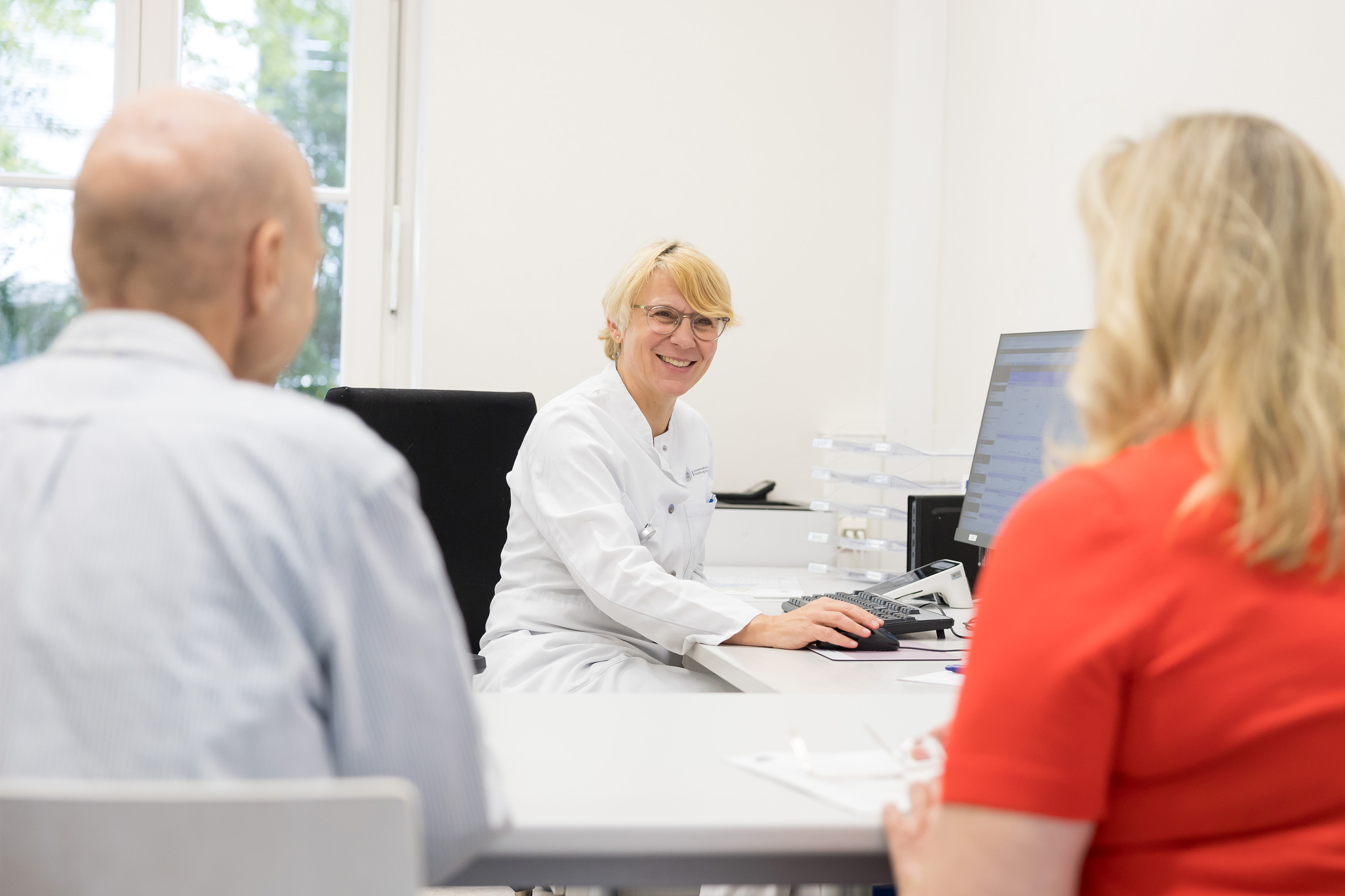 Doctor talking to patient with relatives at a table in a bright room