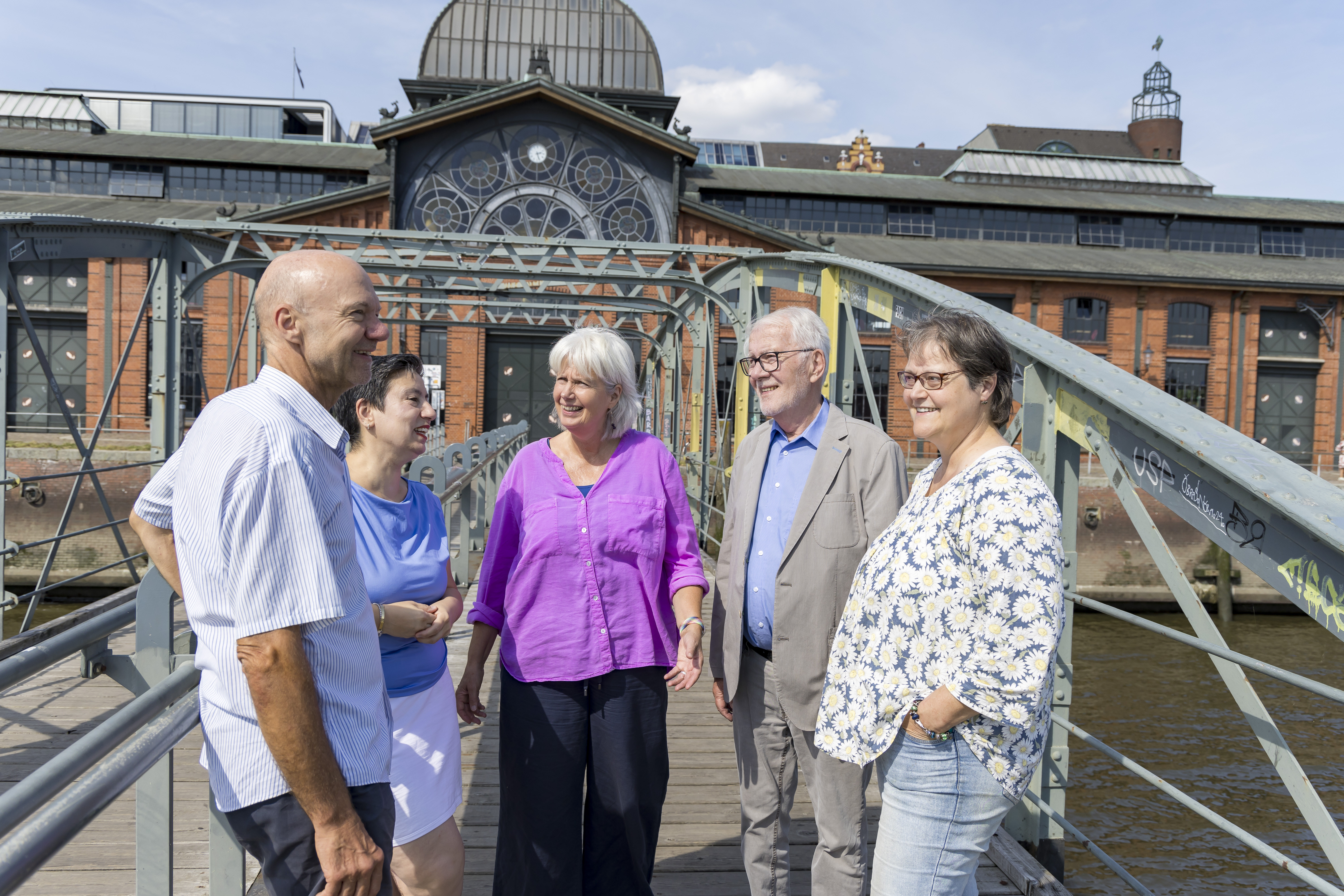 Gruppenbild unserer Patient:innenbotschafter:innen im Gespräch vor der Fischmarkhalle in Hamburg.