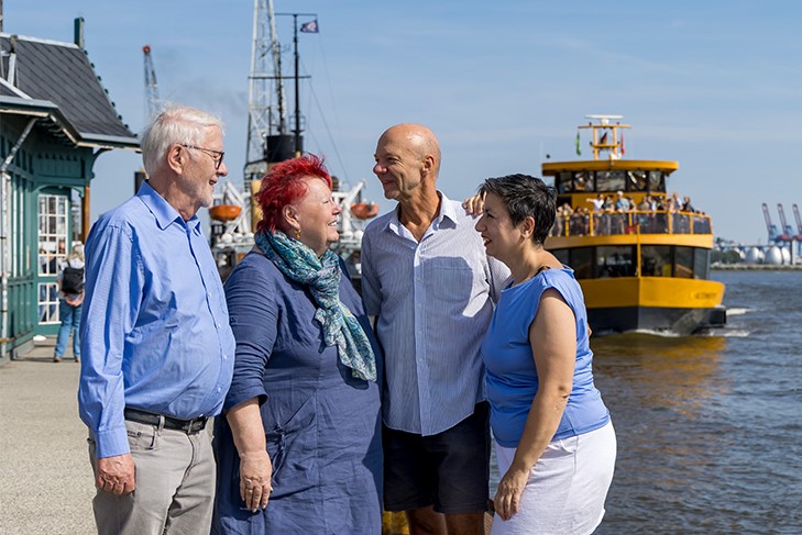 Patient:innenvertreter:innen die sich im Hamburger Hafen vor sonniger Kullise austauschen.