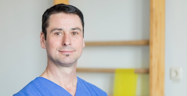 Physiotherapeut vor Sprossenwand